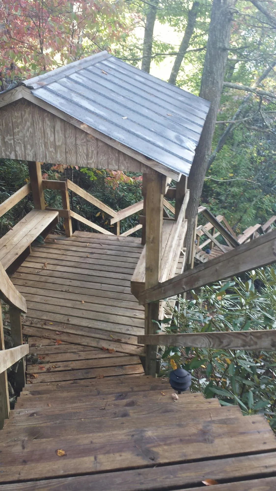 Metal roofed shelter over wooden steps on a wooded walkway — Skylight Repair & Installation work by our crew in Vernal