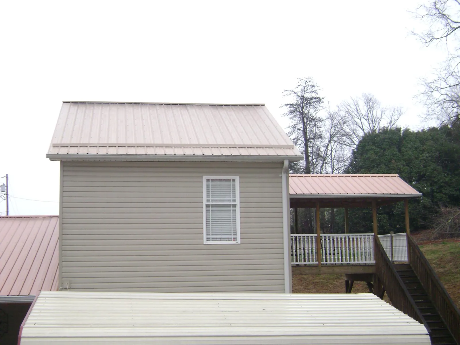 Tan metal roofs on a two story addition and attached porch, from a Roof Replacement job in Vernal